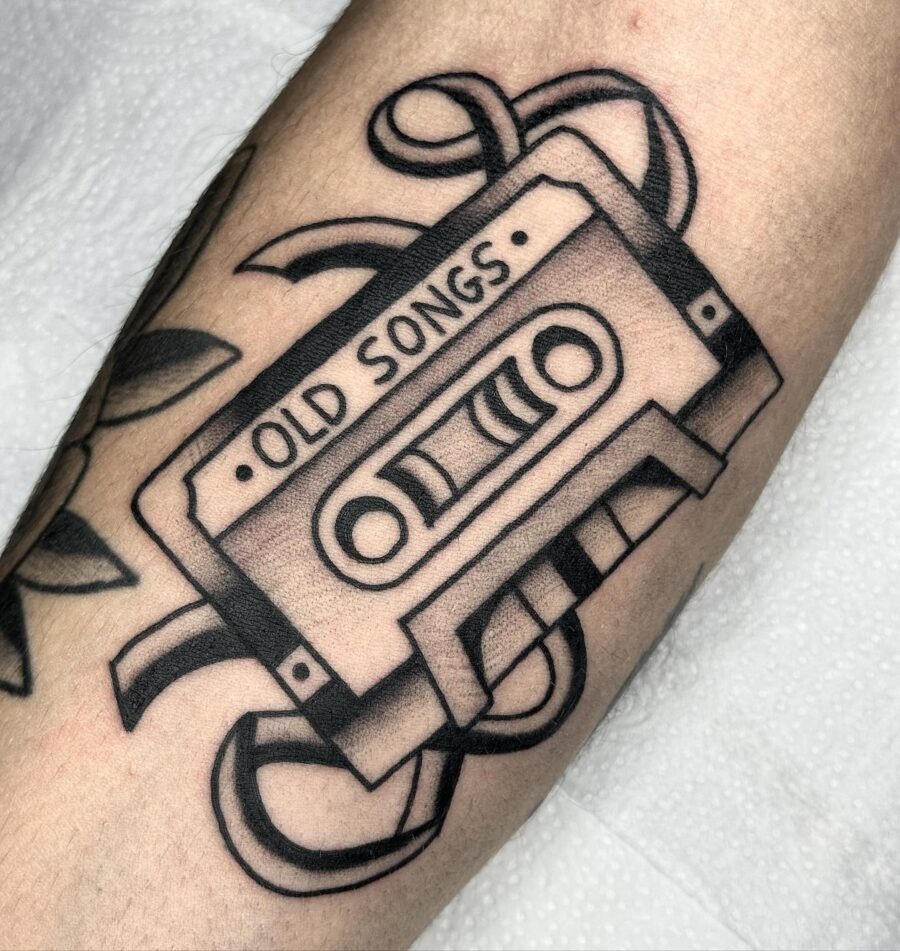 This tattoo showcases a classic cassette tape, artfully designed in black ink.