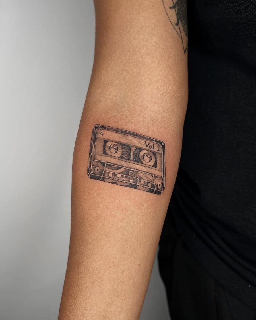 This tattoo features a detailed representation of a cassette tape, highlighting its nostalgic charm.