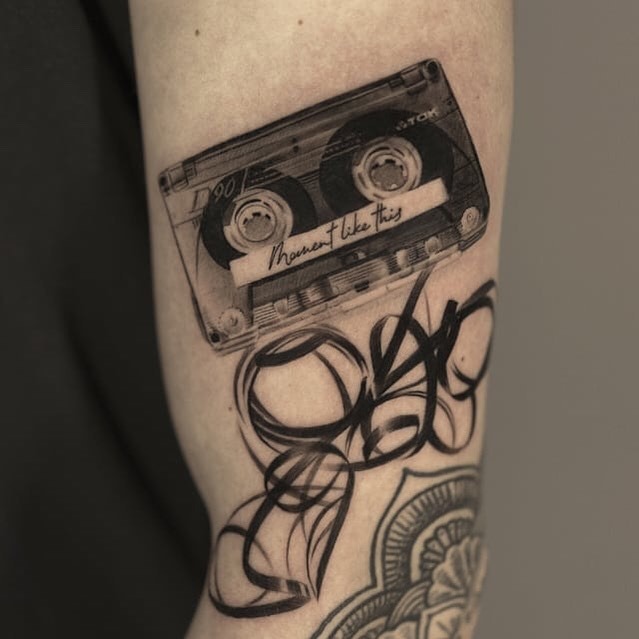 This tattoo features a vintage cassette tape rendered with incredible detail.