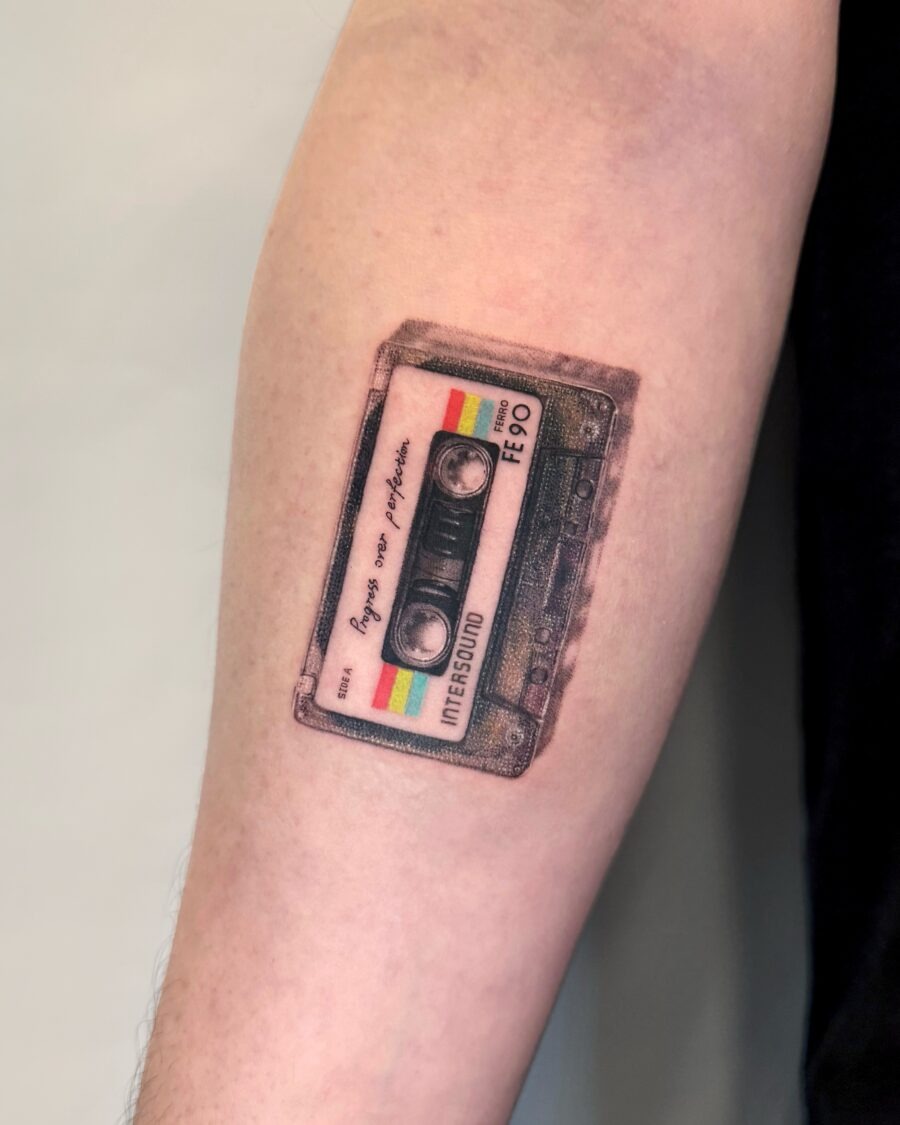 This tattoo features a vintage cassette tape design that captures nostalgia and artistic flair.