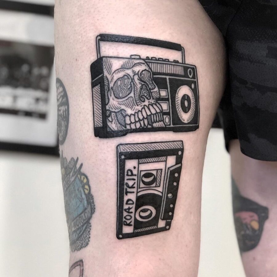 This tattoo features a striking blend of a skull and a cassette tape, capturing a nostalgic vibe.