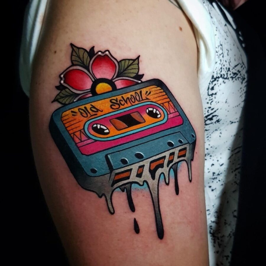 This tattoo showcases a colorful cassette tape dripping with ink, combining nostalgia with artistic flair.