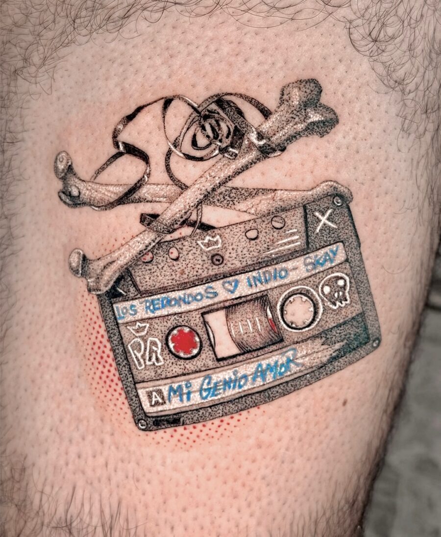 This tattoo showcases a classic cassette tape embellished with skull and crossbones, merging nostalgia with an edgy vibe.