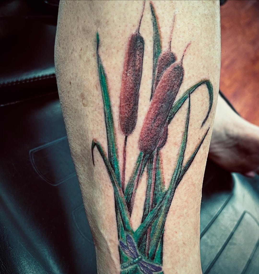 This tattoo showcases three striking cattails, elegantly blending shades of green and brown.