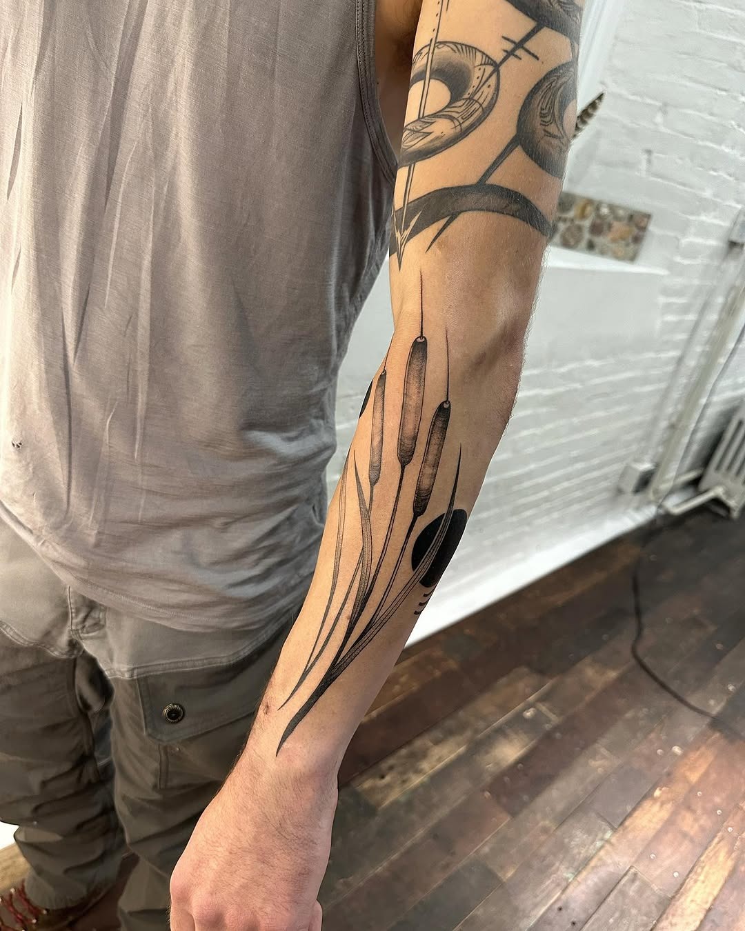 This cattail tattoo showcases slender, flowing lines that embody a natural vibe.