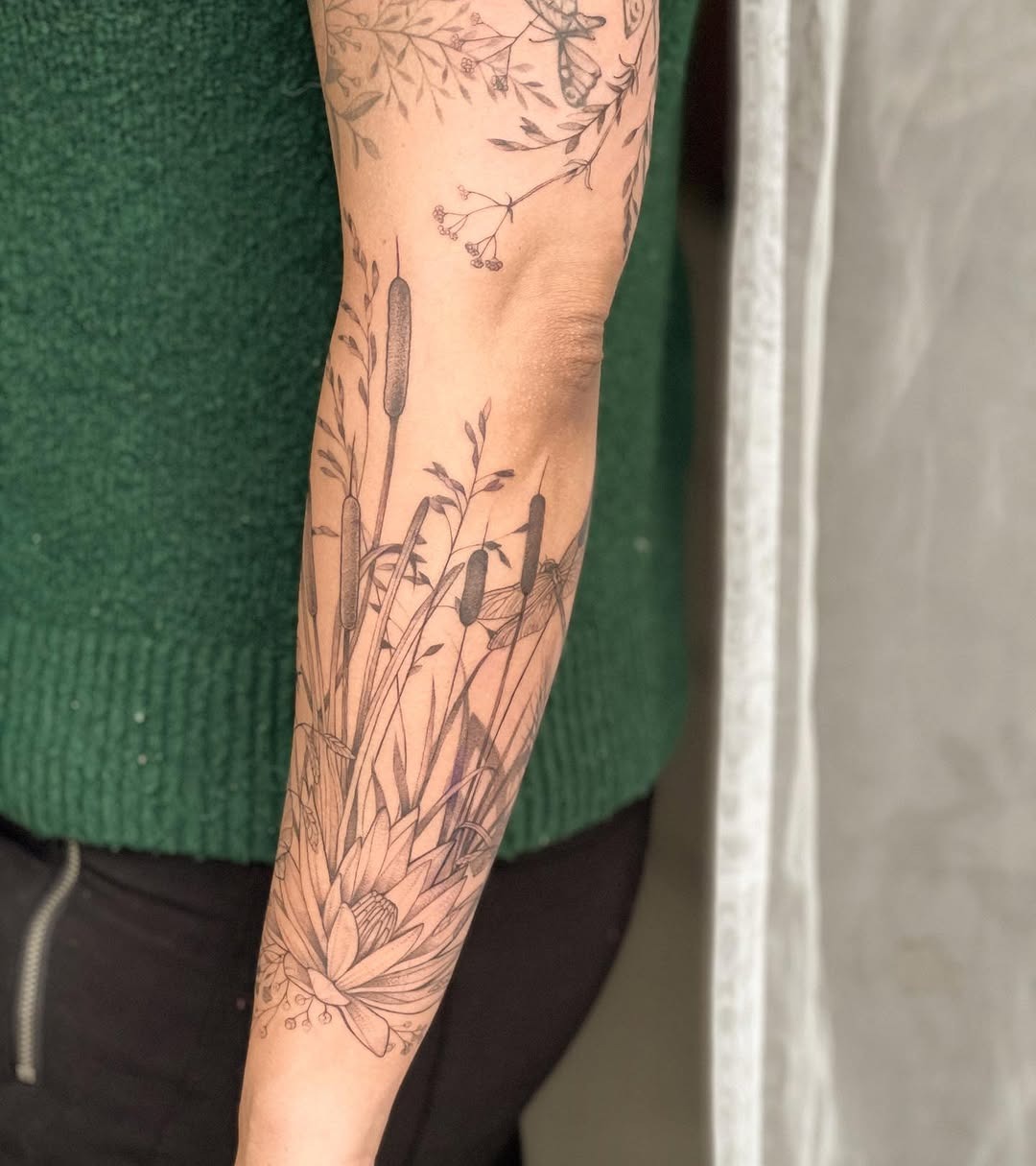 This cattail tattoo elegantly wraps around the arm, celebrating the beauty of nature.