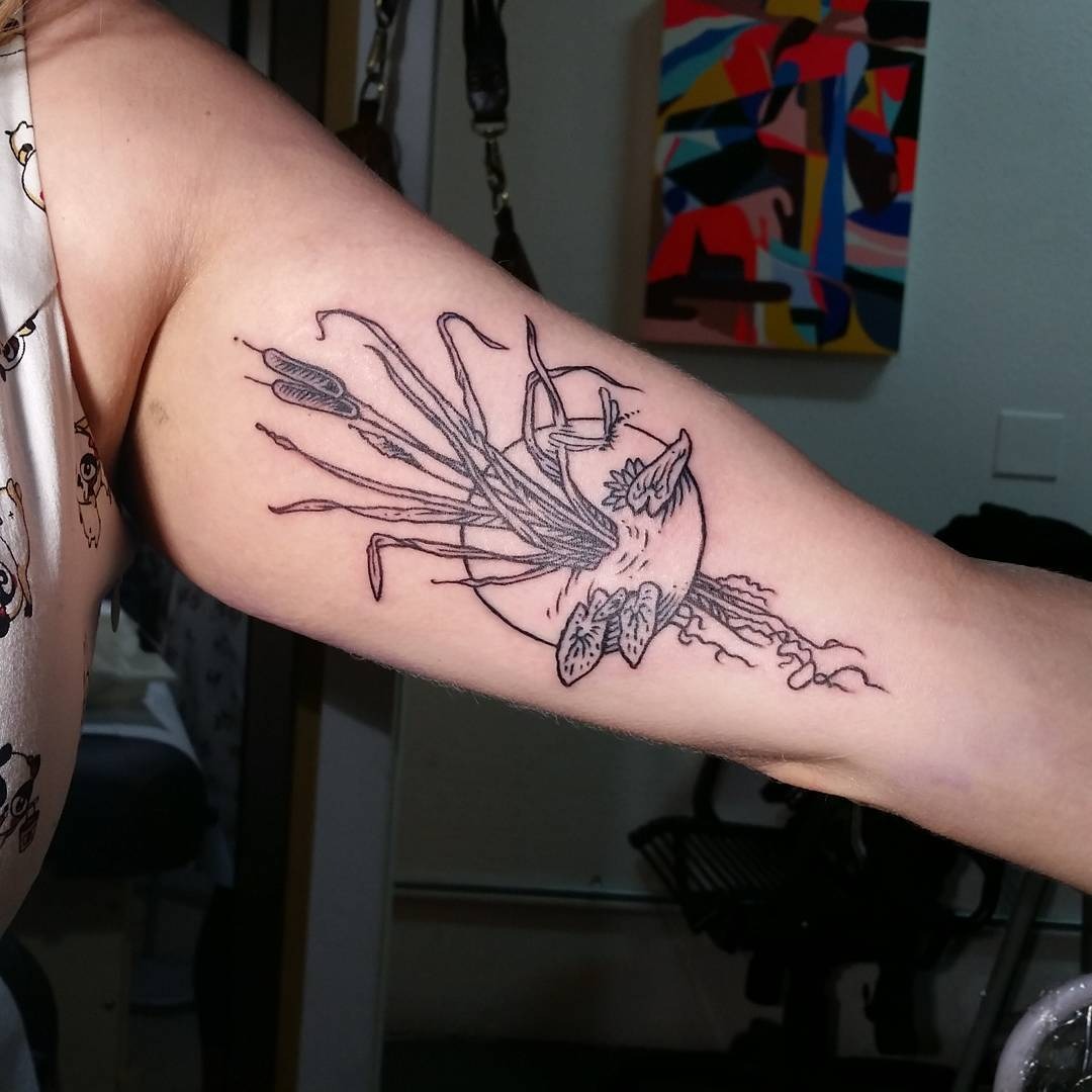 This tattoo showcases a stylized cattail design, highlighted by intricate line work and a flowing composition.