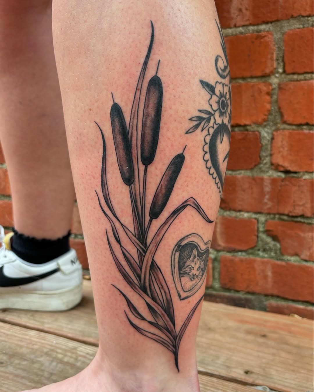This stunning tattoo combines the graceful shape of cattails with a heart design, creating a personal statement.
