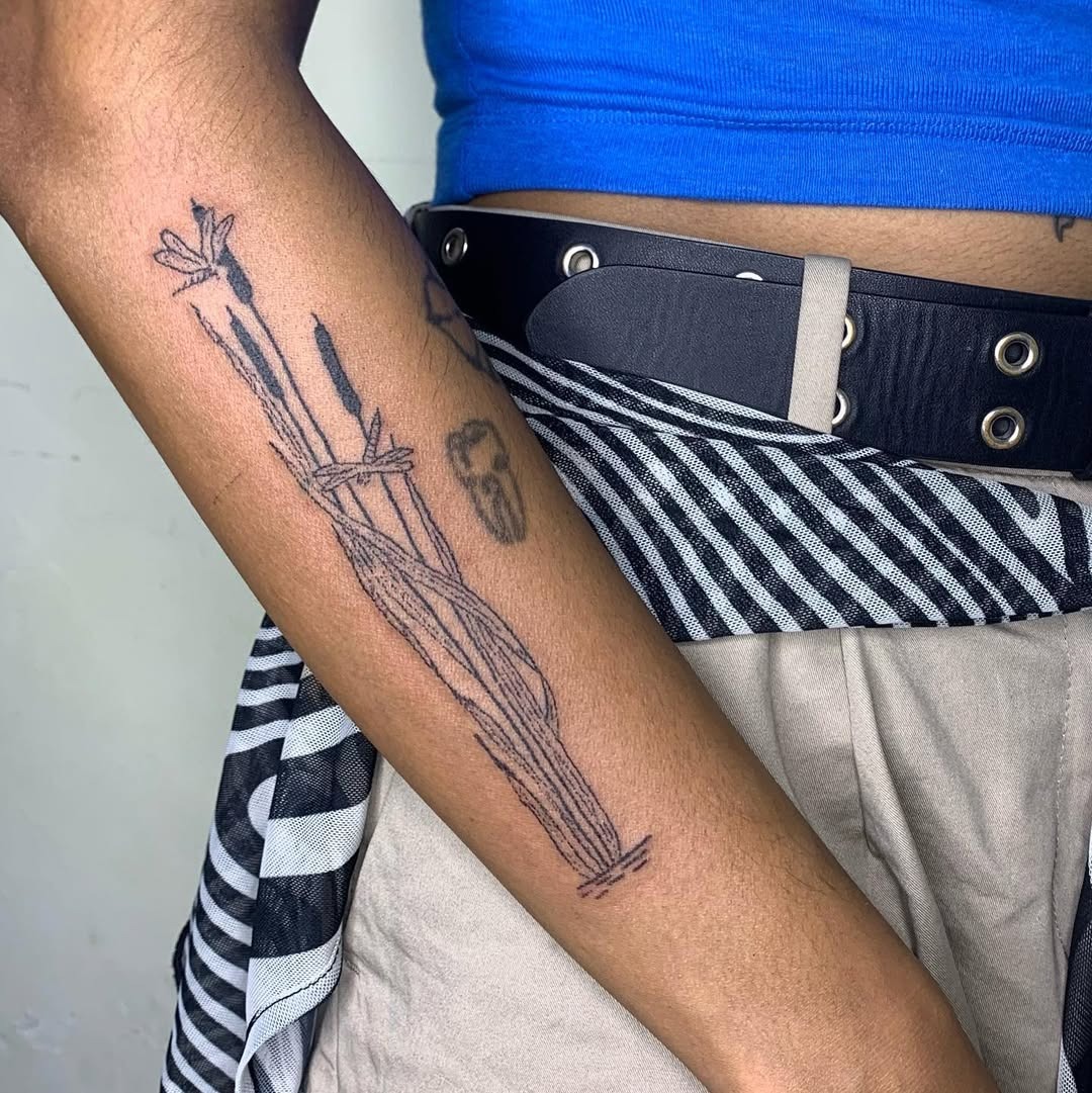 This cattail tattoo features intricate line work and a unique design.