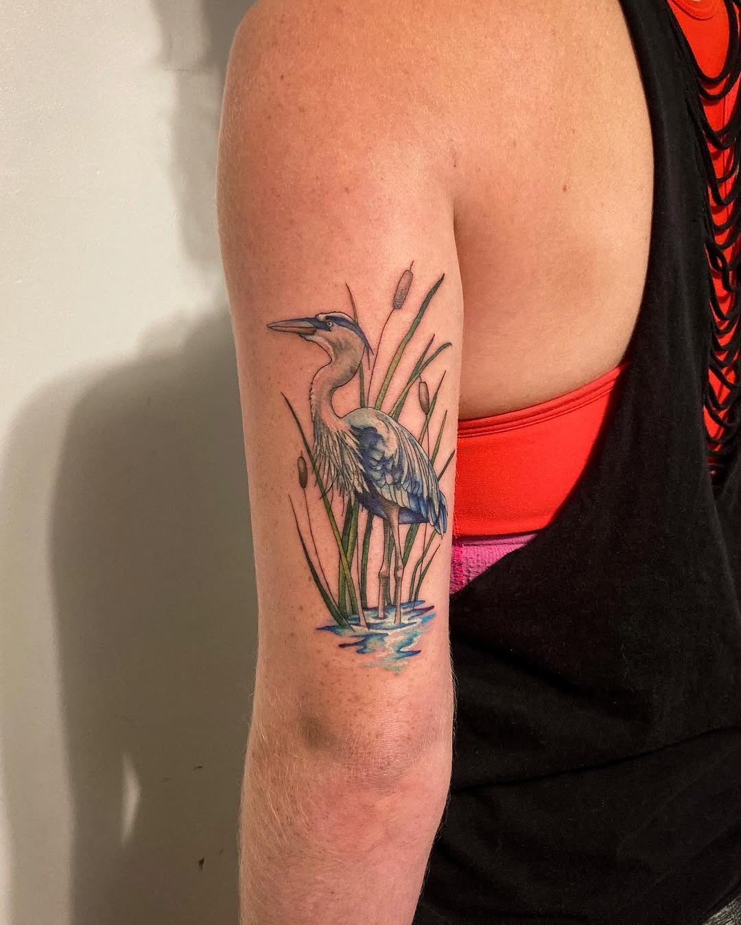 This stunning tattoo features a heron elegantly standing among cattails, embodying nature's grace.