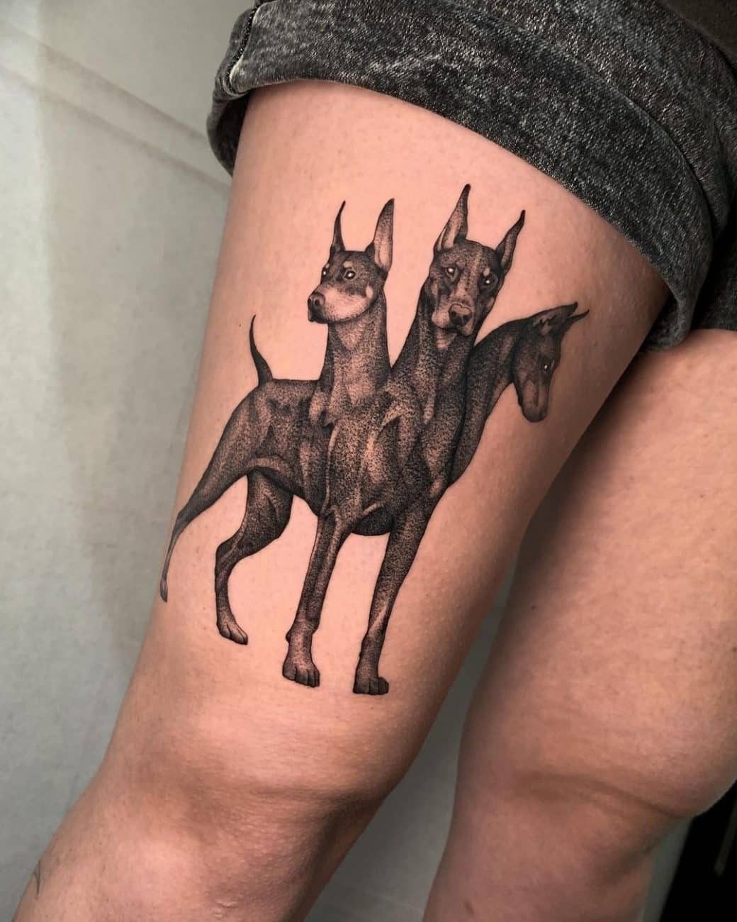 Sleek Cerberus Realism on Thigh Tattoo Design
