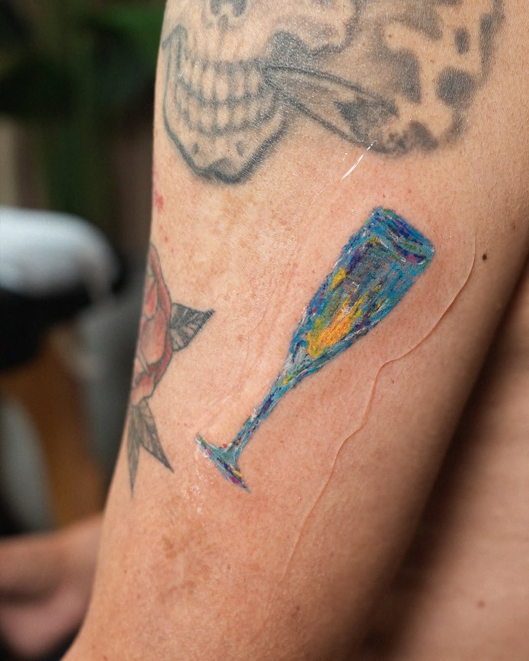 Artful champagne tattoo on a vibrant arm Tattoo Design