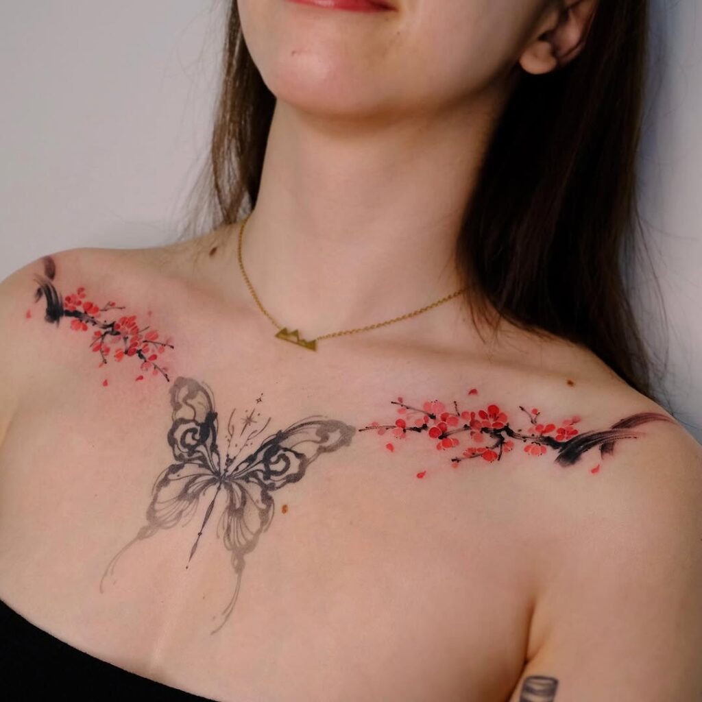 An enchanting collarbone tattoo featuring intricate cherry blossom branches and a stunning butterfly at the center.