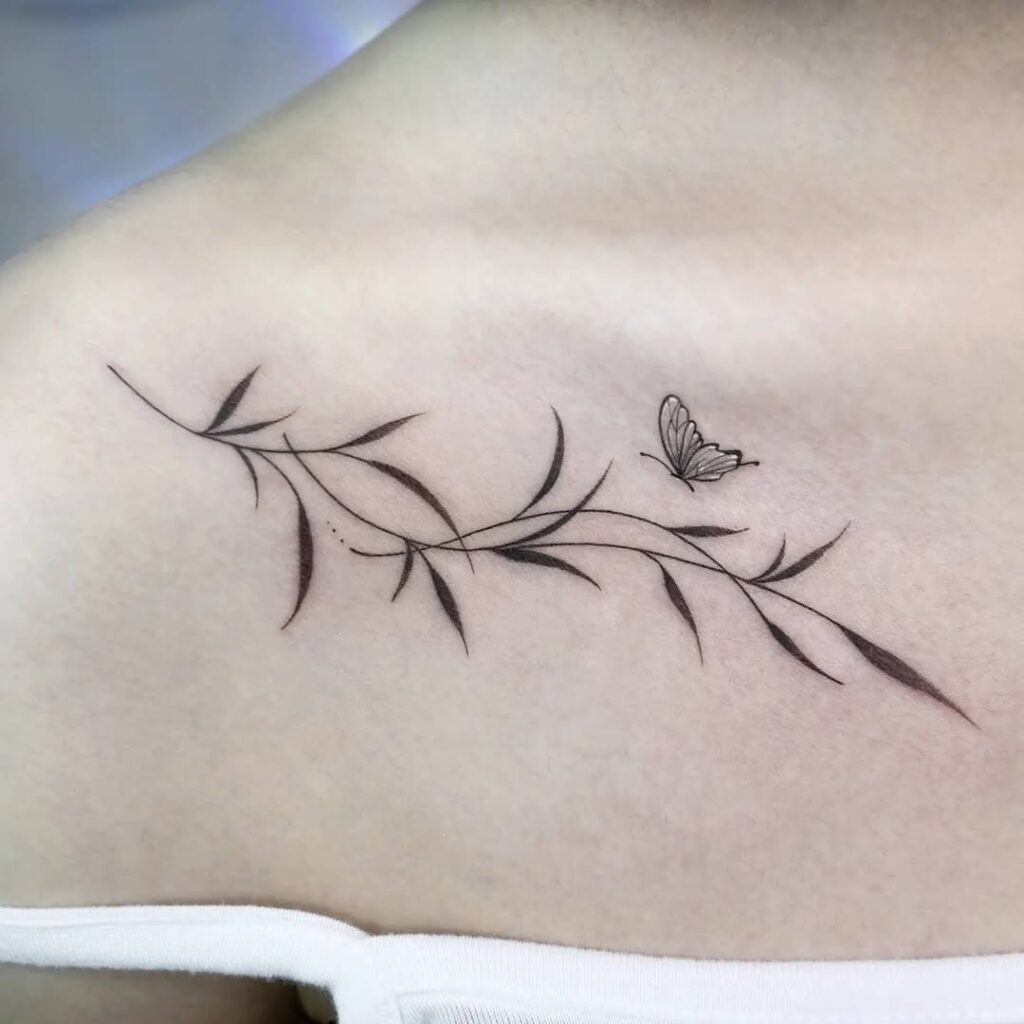 A graceful collarbone tattoo featuring delicate leaves and a small butterfly in fine black linework.