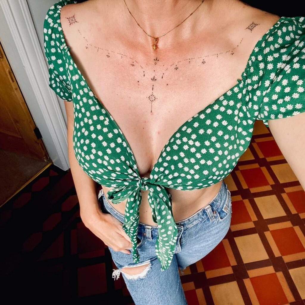 A unique collarbone tattoo featuring intricate dotted patterns that flow symmetrically across the chest.