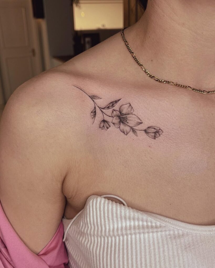 A beautifully soft floral tattoo with intricate black line details, gracefully placed along the collarbone.
