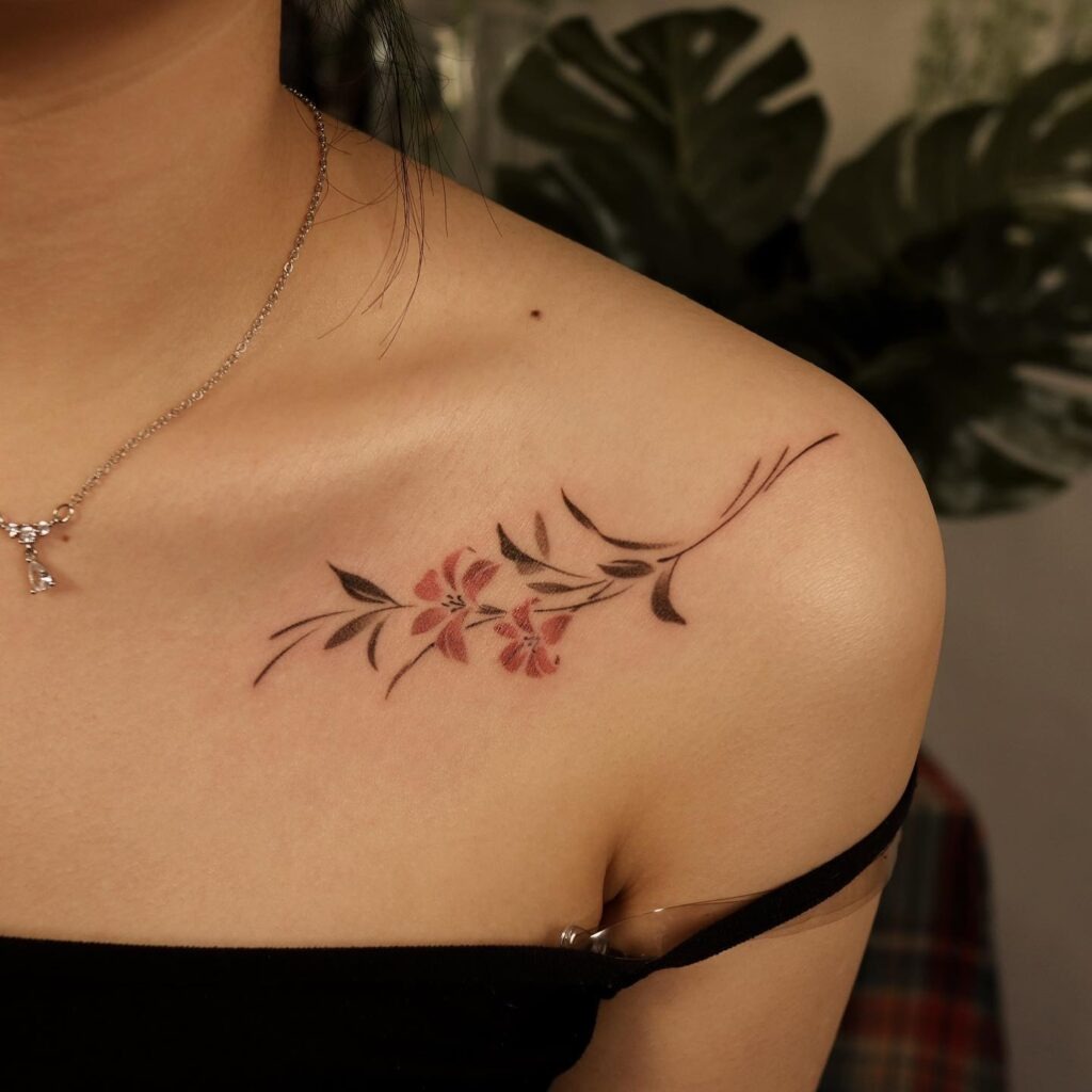 A graceful collarbone tattoo featuring soft pink flowers paired with elegant black leaves.