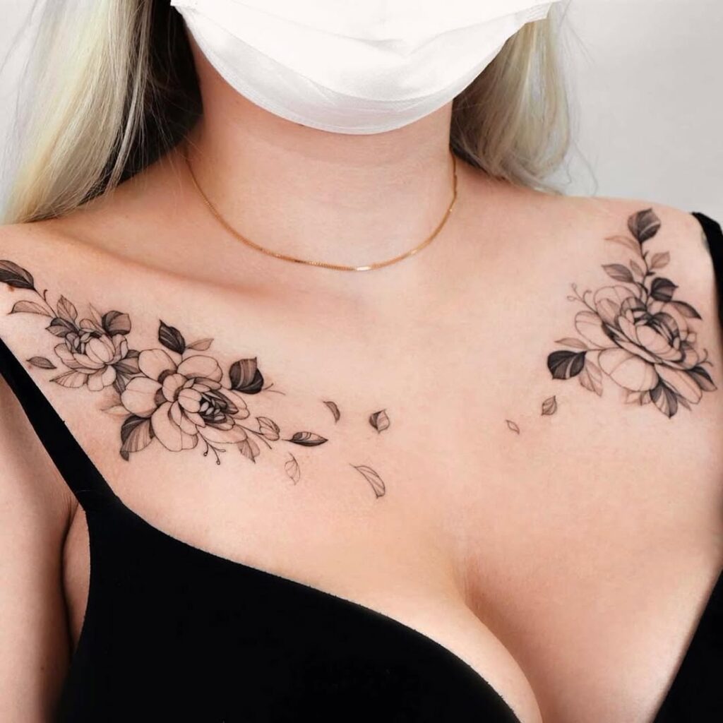 A stunning floral tattoo spanning both collarbones with intricate black and grey shading.