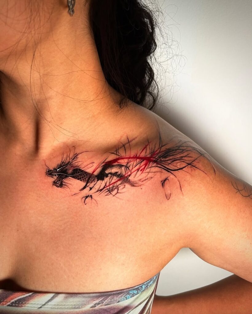 A bold and dynamic tattoo featuring a fierce black dragon with fiery red accents, stretching across the collarbone.