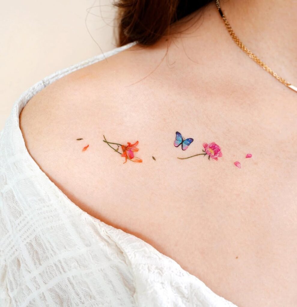 A delicate collarbone tattoo featuring flowers and a colorful butterfly.