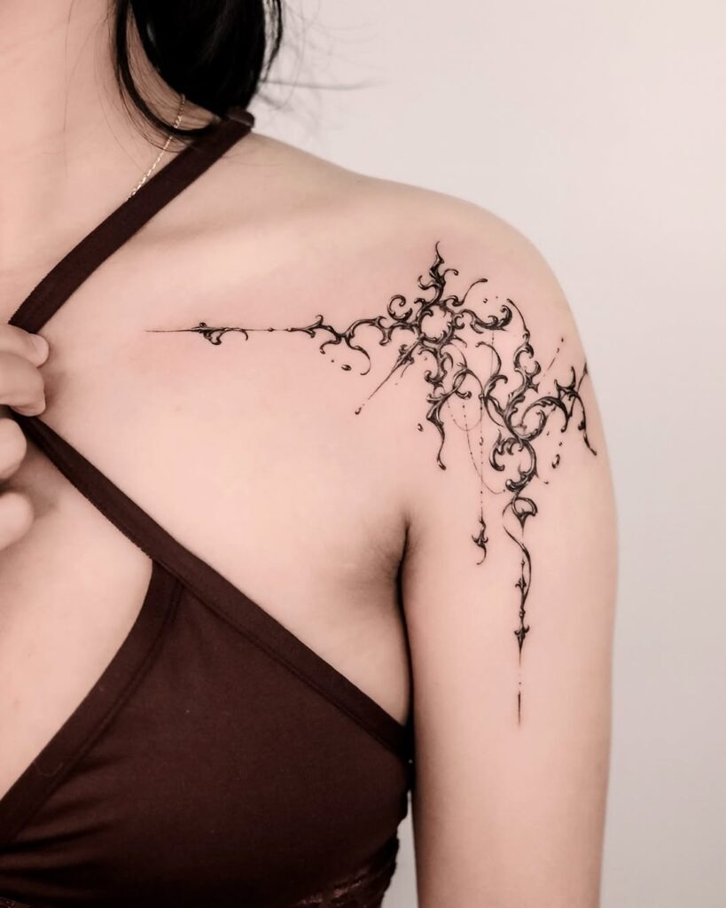 This stunning collarbone tattoo showcases an intricate ornate design with floral-inspired details.