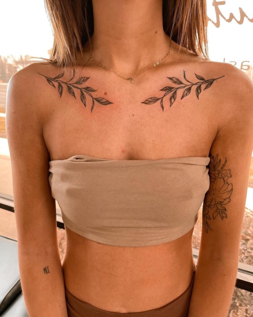 A chic and balanced tattoo featuring leafy vines symmetrically placed on both collarbones.