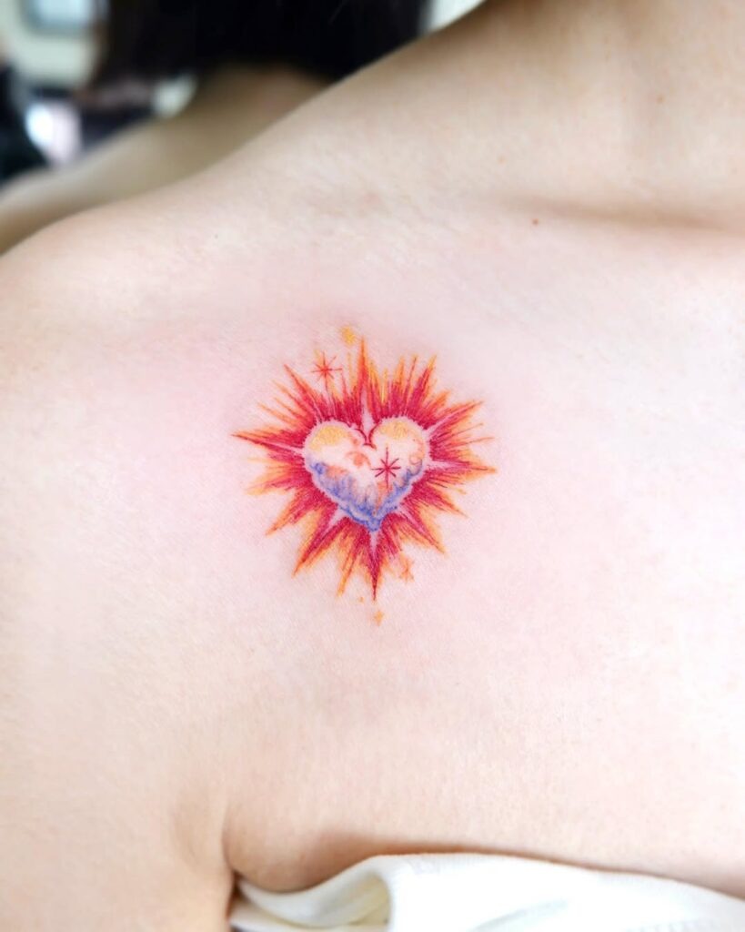 A colorful and radiant heart tattoo placed near the collarbone, featuring bold hues of red, orange, and purple.