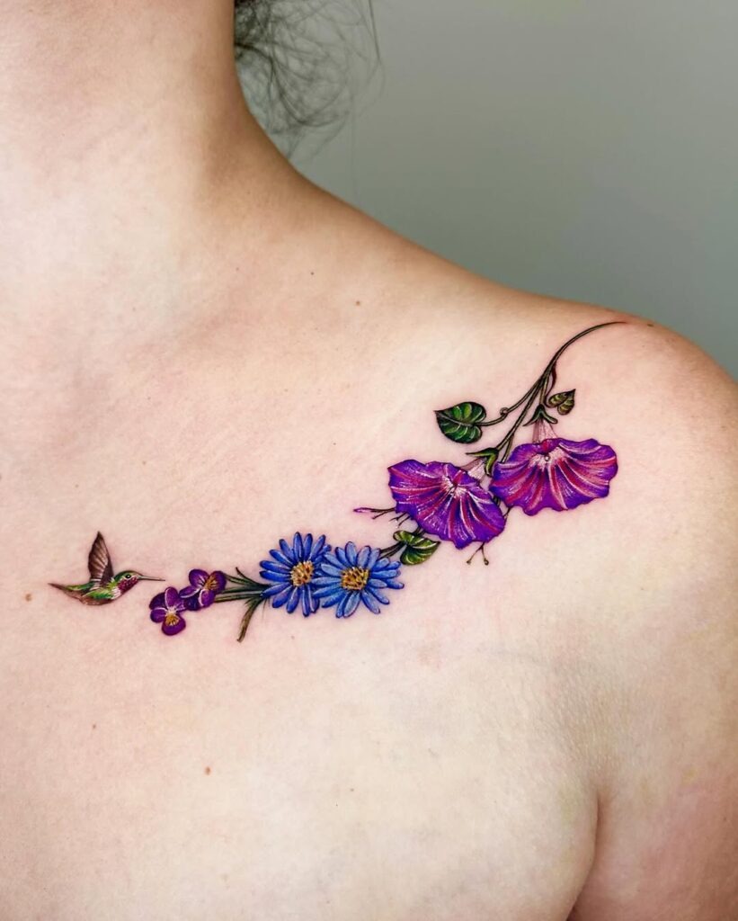 This collarbone tattoo features a colorful array of flowers and a delicate hummingbird in flight.