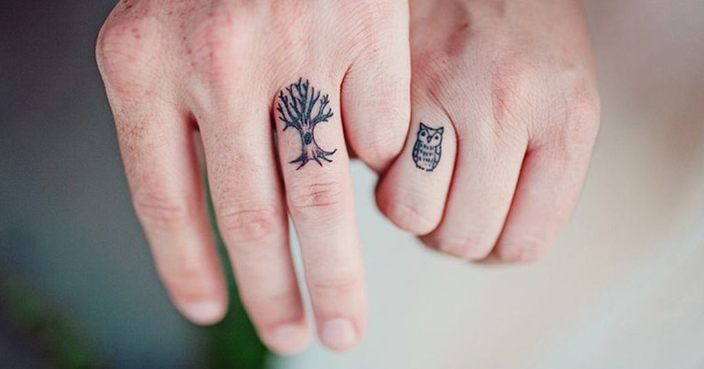 This creative tattoo pairing features a small tree on one partner's finger and an owl on the other's.