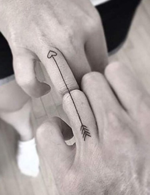 This tattoo design is simple yet powerful, featuring an arrow that ends in a heart on one partner's finger, with the other half of the arrow on the other partner's finger.