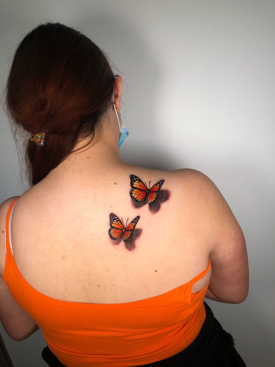 Orange Monarch Butterflies on the Upper Back, a tattoo design rendered in delicate fine-line.