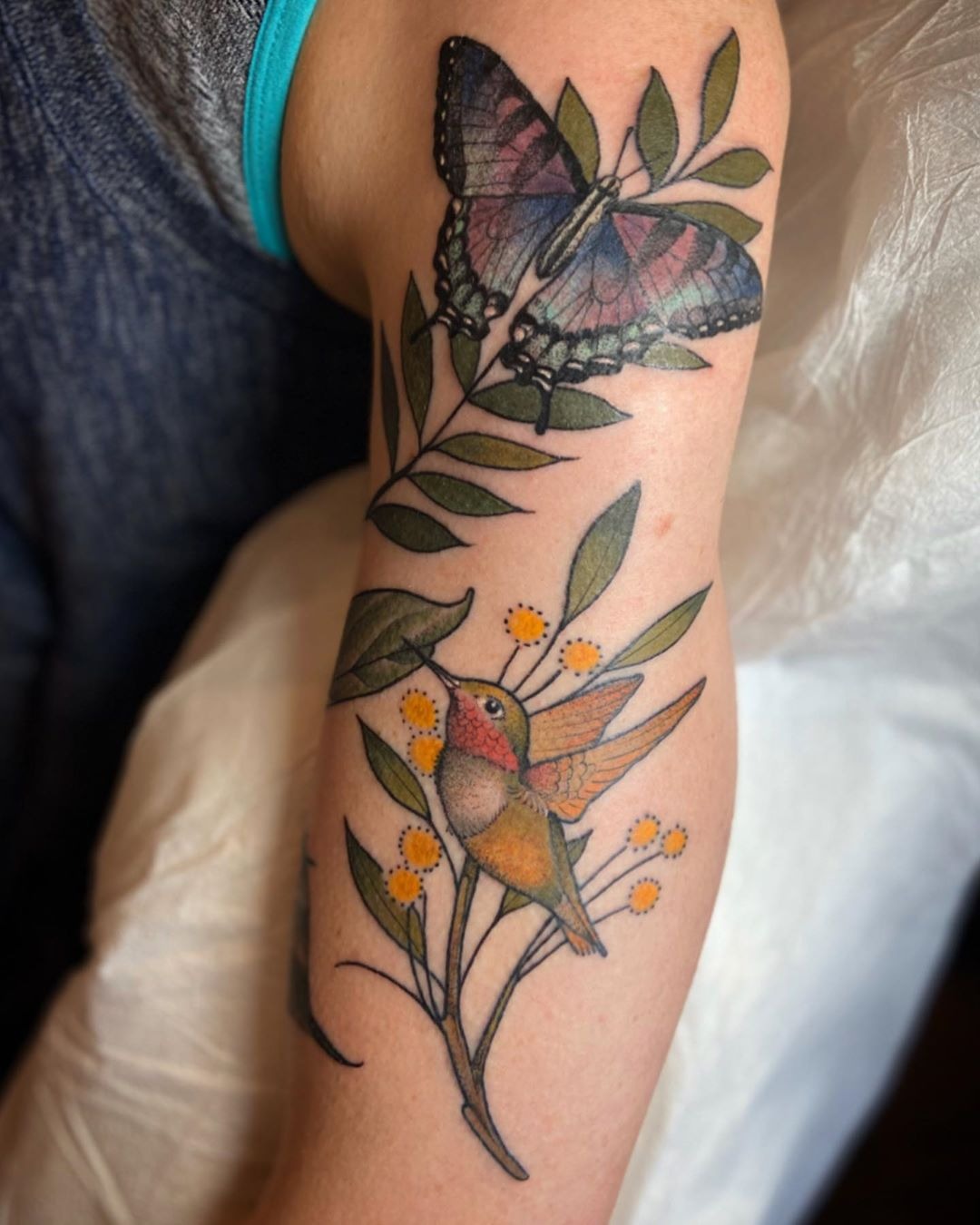 Butterfly and Hummingbird Tattoo Perching on Green Leaves Tattoo Design