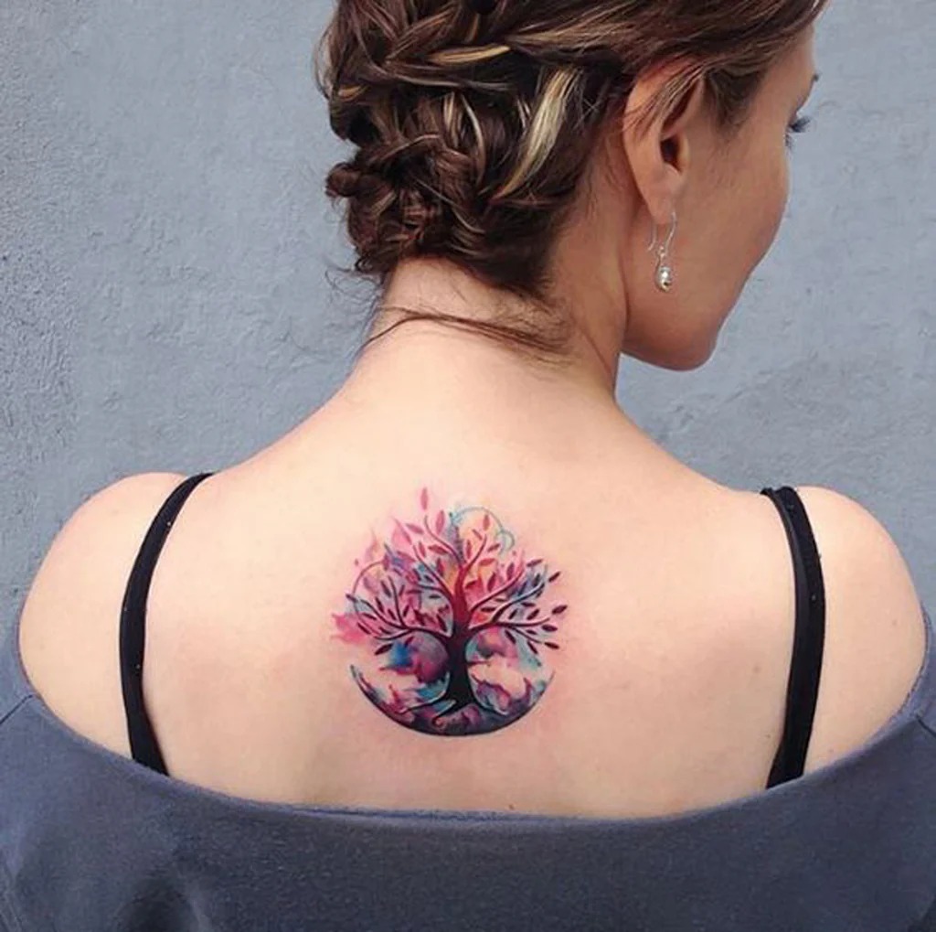 Here, a circular tattoo mirrors the cyclical nature of life, with a tree depicted in a mesmerizing loop of blue and pink hues.