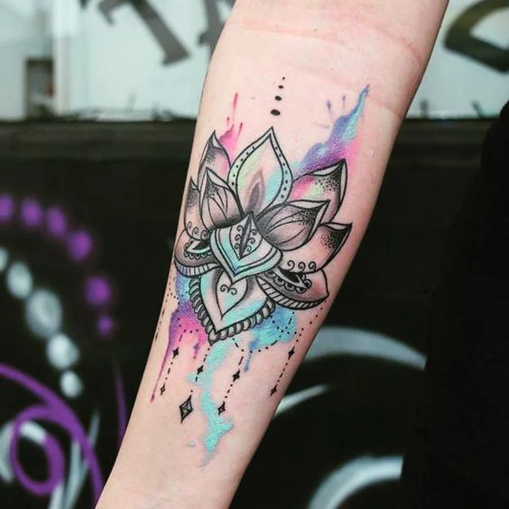 The lotus flower in this tattoo is rendered with exceptional detail, overlaid with watercolor splashes that enhance its spiritual symbolism.