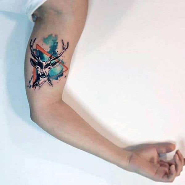Featuring a stag with antlers that transition into colorful, abstract watercolor strokes, this tattoo merges the natural with the surreal.