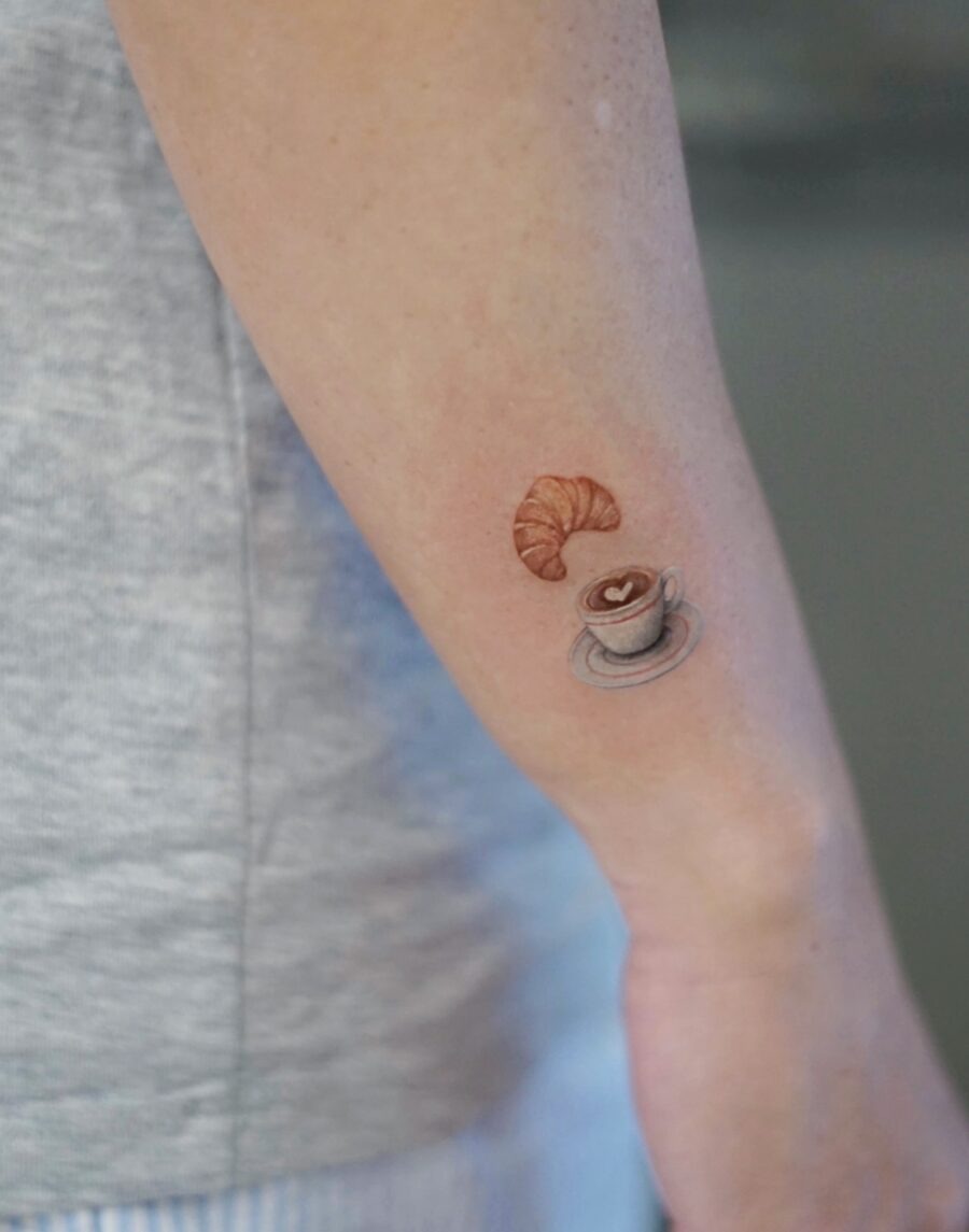 This tattoo features a delightful croissant beside a coffee pour-over.