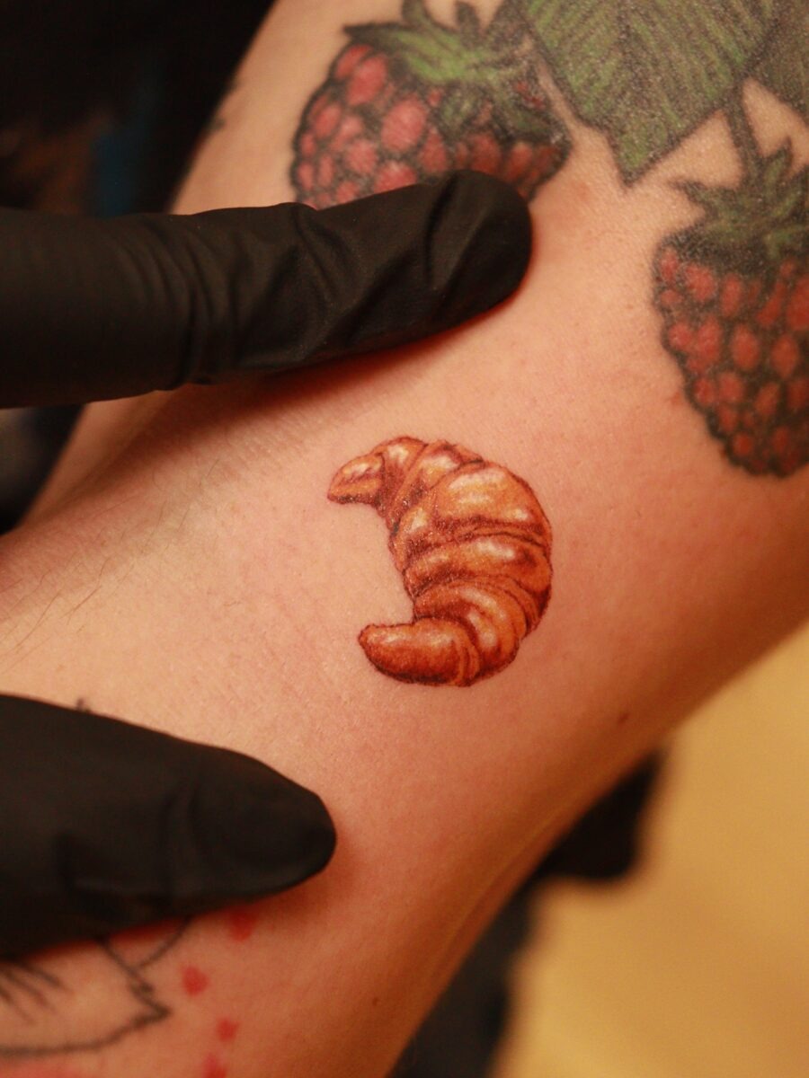 This small croissant tattoo showcases stunning realism.