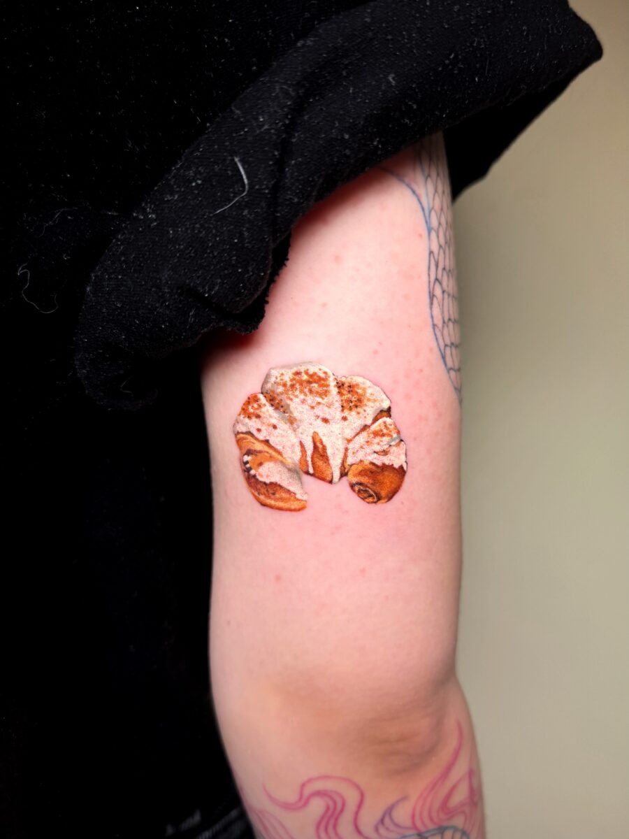 This tattoo features a beautifully detailed croissant, complete with a flaky and textured look.