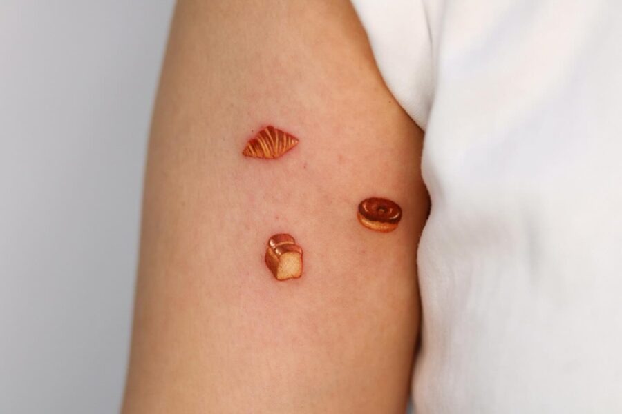 This image showcases delightful croissant tattoos on a person's arm, adding a whimsical touch to their style.