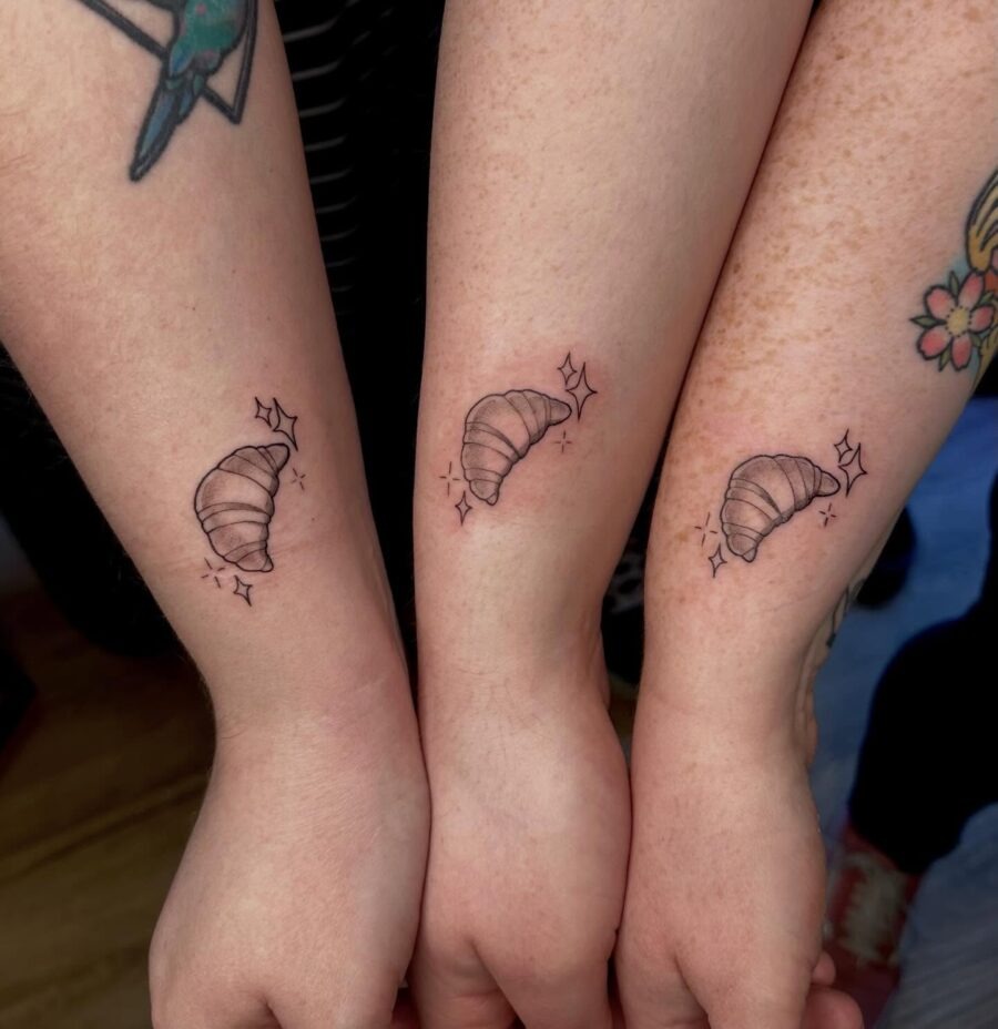 This image features three delicate croissant tattoos inked on the forearms, showing a fun and playful theme.