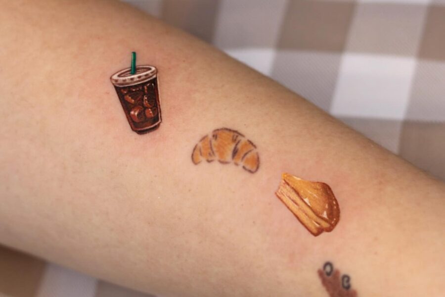 This tattoo showcases a trio of delicious designs, featuring a croissant, an iced drink, and a tempting dessert.