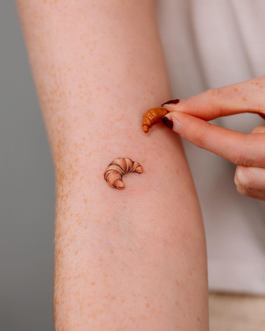This tattoo beautifully captures a croissant's intricate details, offering a lifelike appearance.