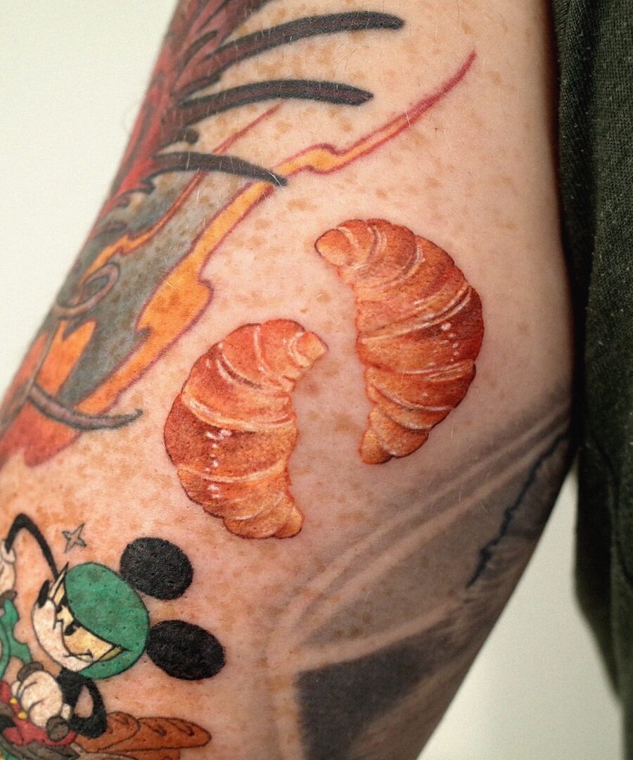 This image showcases two delightful croissant tattoos on an arm.
