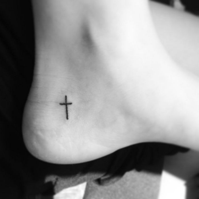 Tiny black cross tattoo on a guy’s heel Tattoo Design