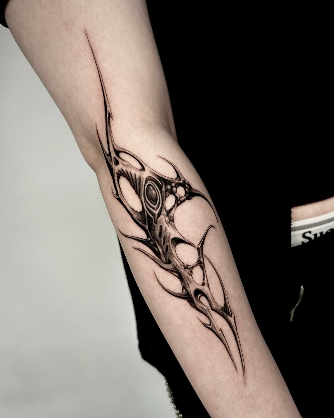 Abstract organic cybersigilism tattoo on forearm with fluid biomechanical curves