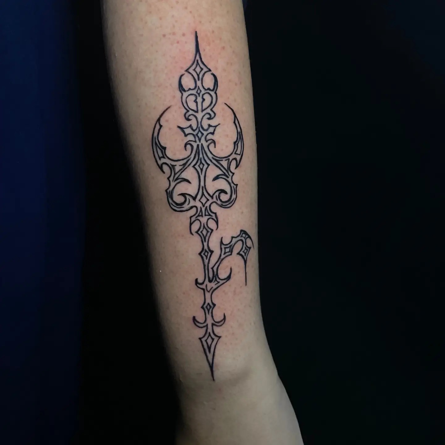 Vertical cybersigilism spear tattoo running down the spine with radiating barb details