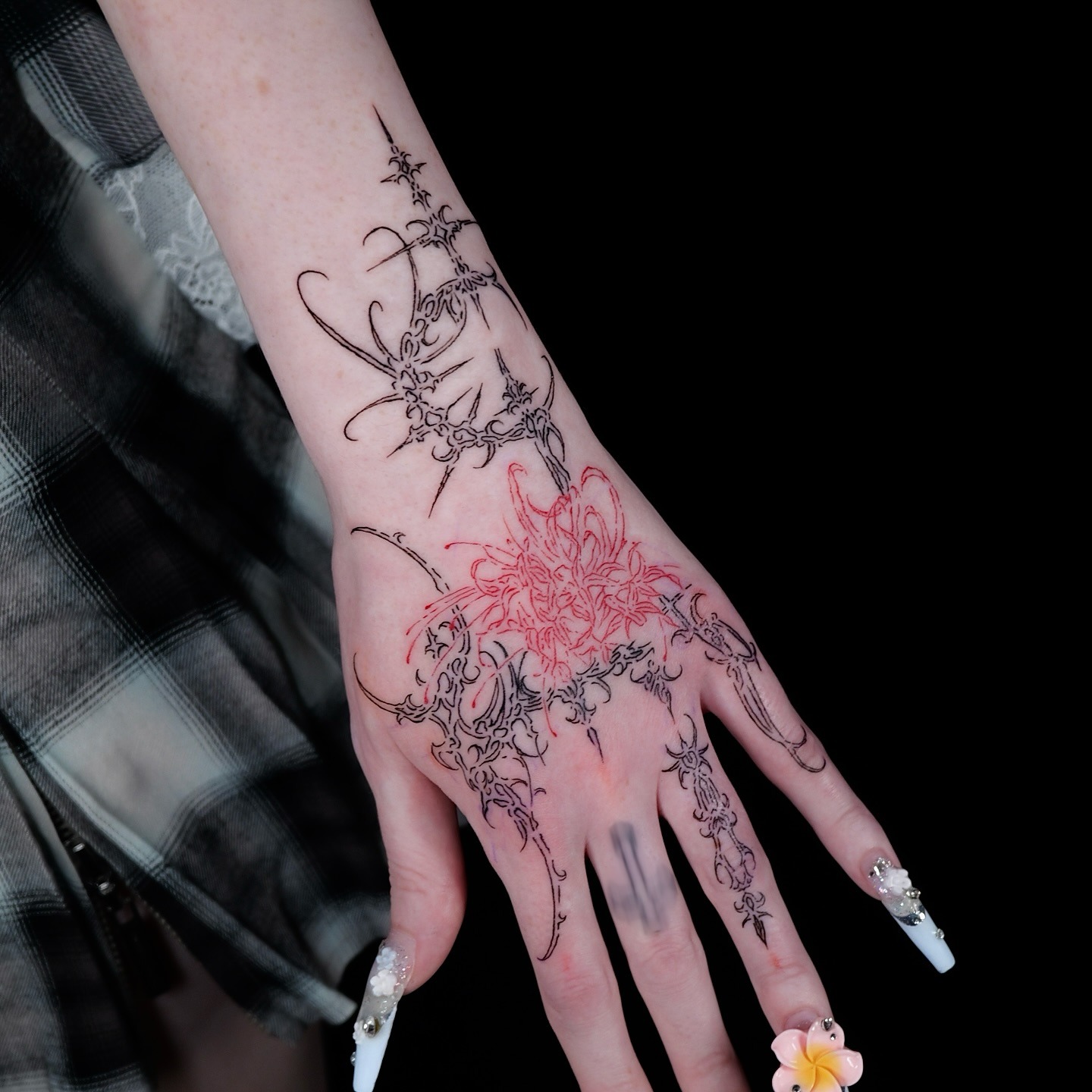 Red spider lily tattoo intertwined with black cybersigilism thorn tendrils on arm