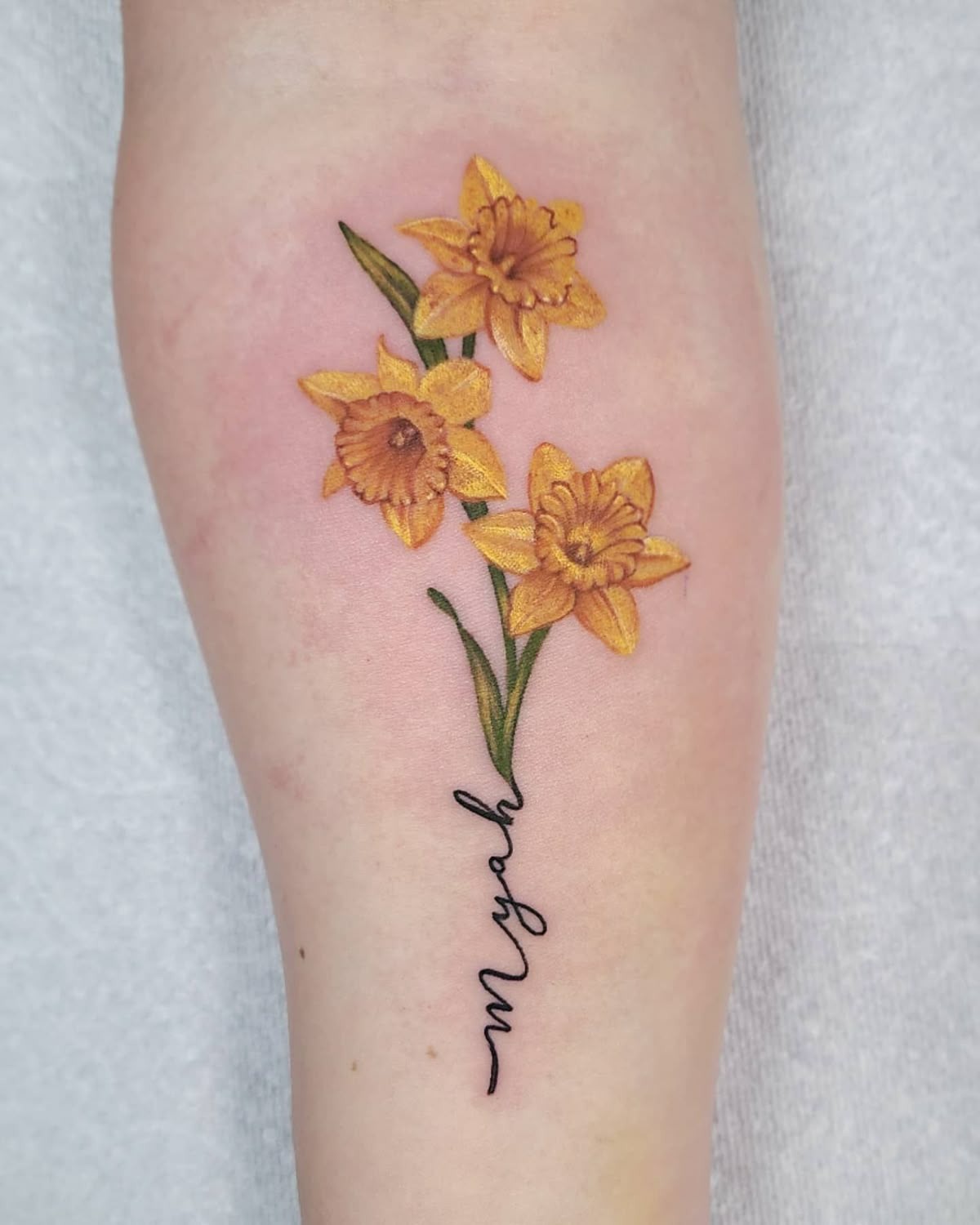 Realistic Yellow Daffodil Trio With Script Stem Tattoo Design
