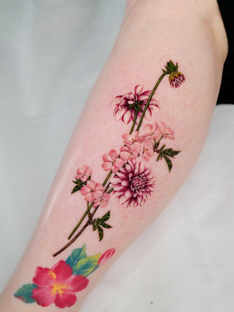 This stunning tattoo features dahlias intertwined with delicate blossoms.