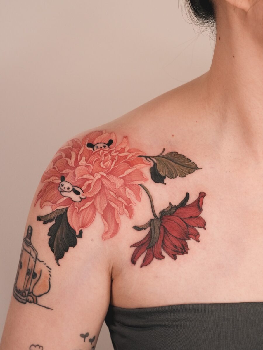This dahlia tattoo features shades of pink and red, capturing the flower's delicate beauty.